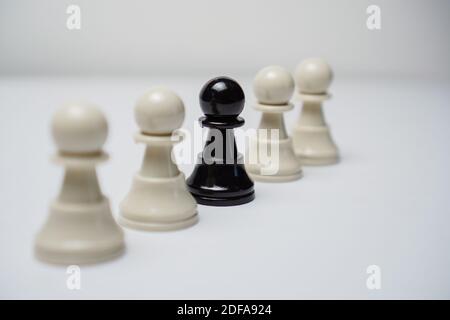 Eine schwarze Spielfigur unter weißen Spielfiguren in einer Linie. Schachkonzept. Stockfoto