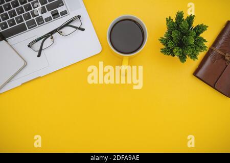 Overhead-Ansicht von Laptop und Kaffeebecher auf gelbem Hintergrund Stockfoto