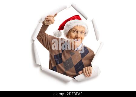 Fröhlicher älterer Mann, der Papier durchbricht und Weihnachten trägt weihnachtsmann Hut Stockfoto