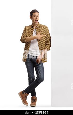 In voller Länge Porträt eines lässigen Mannes in kariertem Hemd Und Jeans, die an einer Wand gelehnt sind und auf die zeigen Seite isoliert auf weißem Hintergrund Stockfoto