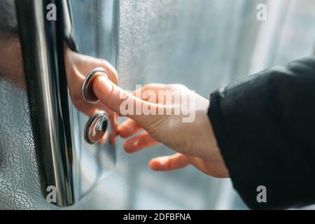 Der Daumen drückt die Elevator-Taste, eine Hand, die nach der Taste greift, das Mädchen wartet auf Elevator, Drucktaste Start, isoliert Stockfoto