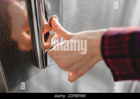 Der Daumen drückt die Elevator-Taste, eine Hand, die nach der Taste greift, das Mädchen wartet auf Elevator, Drucktaste Start, isoliert Stockfoto