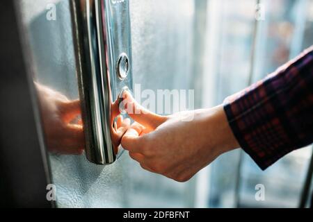 Der Daumen drückt die Elevator-Taste, eine Hand, die nach der Taste greift, das Mädchen wartet auf Elevator, Drucktaste Start, isoliert Stockfoto