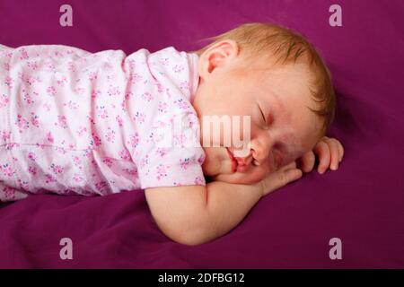 Neugeborenes Baby Mädchen trägt rosa Kostüm schlafen in einer Wiege Im Freien Stockfoto