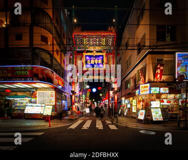 Die Menschen passieren eines der vielen Torii-Tore in Chinatown in Yokohama, Japan; Japans zweitgrößte Stadt. Stockfoto