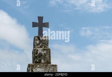 Schönes Foto des heiligen Kreuzes auf der Oberseite der Vintage-Säule mit blauem Himmel und spärlichen weißen Wolken im Hintergrund fixiert. Stockfoto