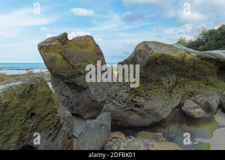 Typische Beach Rock Struktur, aus großen schwarzen basaltischen und Igneous Felsen an der Küste. Von Jahrhunderten durch Wellen und Lebensraum von Organismen erodiert Stockfoto