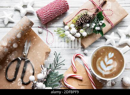 Weihnachts- und Glückskarte mit Tasse Kaffee, Kiefer, Tanne, Geschenkschachteln auf weißem Holzhintergrund, Draufsicht Stockfoto