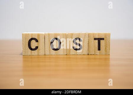 Holzklotz auf dem Schreibtisch mit dem Wort Kosten. Stockfoto