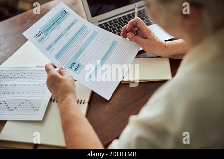 Ältere Frau, die zu Hause das Steuerformular ausfüllt Stockfoto