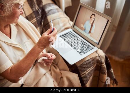Ältere Frau mit Online-Beratung mit Arzt zu Hause Stockfoto
