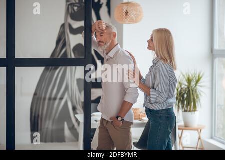 Bärtiger Mann sieht traurig aus, blonde Frau unterstützt ihn Stockfoto