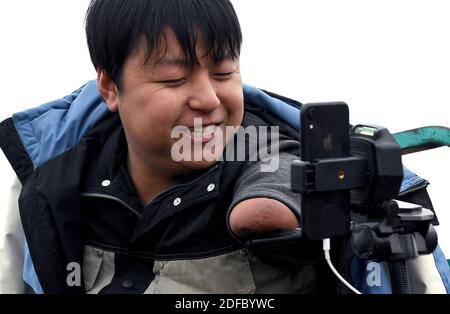 (201204) -- ZHENGZHOU, 4. Dezember 2020 (Xinhua) -- Sun Yahui interagiert mit seinen Anhängern, während er an einem entwässerten Teich im Dorf Wanglu in Xinxiang, der zentralchinesischen Provinz Henan, am 2. Dezember 2020 Livestream macht. „Hallo, alle! Heute werde ich dir zeigen, wie man Lotuswurzeln im Dorf meines Onkels gräbt." Als ein neuer Tag begann, stellte Sun Yahui das Handy mit seinem linken Bein bereit und begann seine Livestreaming. Sun Yahui, 26, verlor beide Arme und wurde vor 4 Jahren durch elektrische Verletzungen gelähmt. "Ich dachte, ich wäre nutzlos." Der Unfall hinterließ Verletzungen am Körper und emotionale Narben am Geist. Um seine Wunden zu behandeln Stockfoto