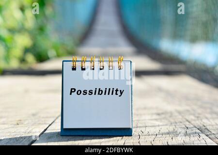 Möglicher Text auf weißer Note mit verschwommenem Hintergrund der Hängebrücke geschrieben. Positive Worte Stockfoto