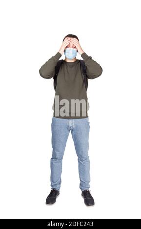 In voller Länge Porträt von erschöpft Mann trägt Gesichtsmaske, hält die Hände auf Stirn, isoliert auf weißem Hintergrund. Casual guy Prävention Maßnahme gegen Stockfoto