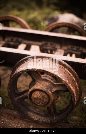 Nahaufnahme der rostigen Metallräder eines verlassenen Wagens. Stockfoto