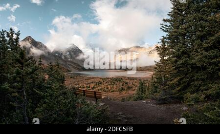 Landschaft des Mount Assiniboine mit See magog im Herbst Wald und Holzbank am Aussichtspunkt. British Columbia, Kanada Stockfoto