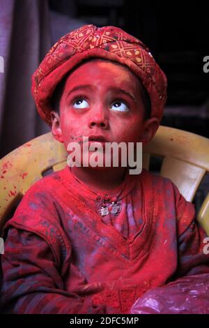 Indien, Kinderporträt in roten Holi-Farben während Holi-Feiern in Vrindavan bedeckt Stockfoto