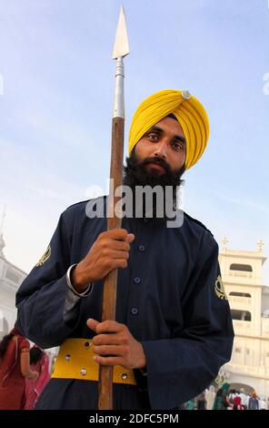 Indien, Amritsar, Sikh Mann mit Speer und safranfarbenen Turban im goldenen Tempel Stockfoto