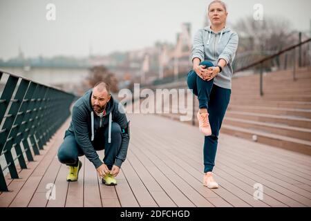 Freunde dehnen sich nach dem Joggen. Gruppe von Freunden Joggen am Morgen in der Nähe des Flusses Stockfoto