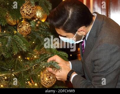 London, Großbritannien. Dezember 2020. Mann mit Maske passt eine Kugel auf dem Weihnachtsbaum an.das Savoy Hotel hat eine neue Weihnachts-Charity-Initiative eröffnet - Festliche Wünsche. Das Savoy, das mit der Präsentation seiner berühmten Weihnachtsdekoration ins Leben gerufen wurde, wird dem Gast die Wohltätigkeitsorganisationen „Hospitality Action“ und „The Connection at St. Martin in the Fields“ schenken und damit zwei wichtige Wohltätigkeitsorganisationen unterstützen. Kredit: SOPA Images Limited/Alamy Live Nachrichten Stockfoto