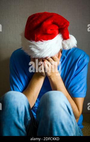 Trauriger Mann in Santa hat verstecken ein Gesicht bei der Wand Stockfoto