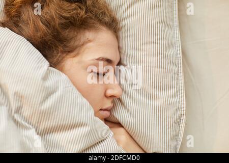 Nahaufnahme einer Frau, die unter der Decke im Bett schläft Stockfoto