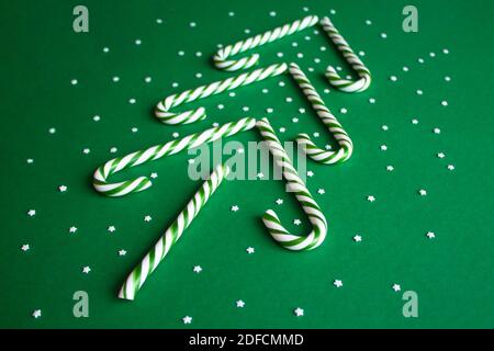 Weihnachtsbaum aus Zuckerstöcken. Grüne Süßstäbchen mit kleinen Sternen. Flach liegend, Ansicht von oben. Poster, Banner, Grußkartenvorlage. Festlicher Rücken Stockfoto