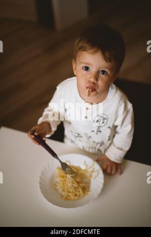 Netter kleiner Junge, der zu Hause Spaghetti isst Stockfoto