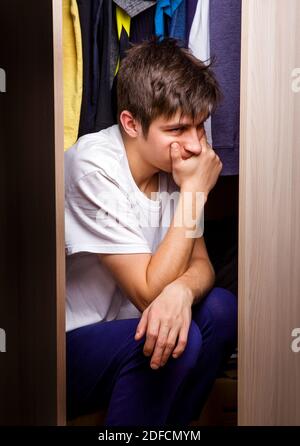 Trauriger junger Mann sitzt in der Garderobe des Hauses Stockfoto