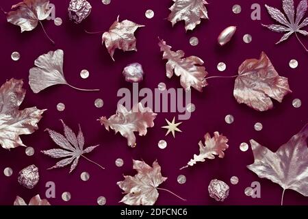 Autumn leaves with metallic golden paint. Flat lay on dark burgundy color linen textile background. Stockfoto
