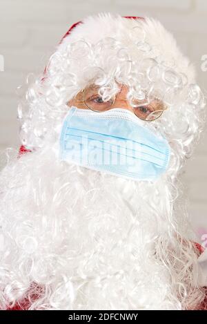 Mann im Santa claus Kostüm trägt Sicherheitsgaze medizinische Gesichtsmaske. Stockfoto