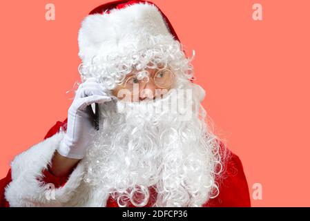 weihnachtsmann mit Handy isoliert auf rosa Hintergrund Stockfoto