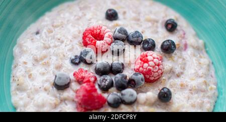 Haferflocken Haferbrei in einem Teller mit Johannisbeere und Himbeere Beeren. Nützliches Frühstück zu Beginn des Tages. Stockfoto