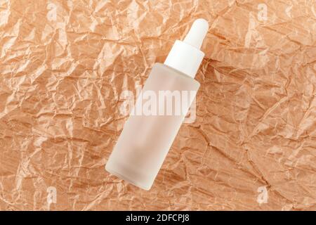 Hyaluronsäure-Tinktur auf gefaltetes Karton. Serum mit Kollagen und Peptiden auf zerknittertem Papier. Anti-Age-Produkt, Luxus-Körperpflege-Konzept Stockfoto