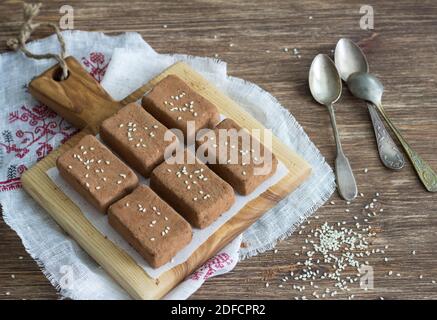 Schokolade Süßigkeiten mit getrockneten Früchten und Sesam auf einem Holzbrett auf einem Holztisch, rustikalen Stil. Gesunde hausgemachte Speisen Stockfoto