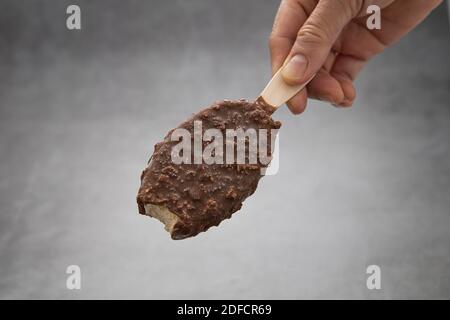 Eine Frauenhand hält eine Schokolade Popsicle klebt mit ein bisschen einen Bissen. Stockfoto
