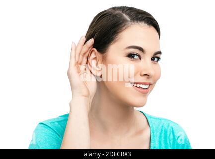 Hörtestkonzept. Positive hispanische Frau hält Hand in der Nähe des Ohrs, isoliert auf weißem Hintergrund Stockfoto