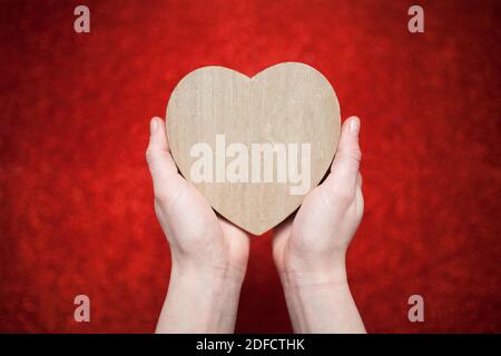 Ein funkelnder roter Hintergrund, Strass, Valentinstag Geschenk für die zweite Hälfte, ein romantisches Foto, ein hölzernes Herz auf einem roten Hintergrund, geeignet für te Stockfoto