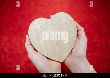 Ein funkelnder roter Hintergrund, Strass, Valentinstag Geschenk für die zweite Hälfte, ein romantisches Foto, ein hölzernes Herz auf einem roten Hintergrund, geeignet für te Stockfoto