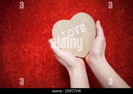 Ein funkelnder roter Hintergrund, Strass, Valentinstag Geschenk für die zweite Hälfte, ein romantisches Foto, ein hölzernes Herz auf einem roten Hintergrund, geeignet für te Stockfoto