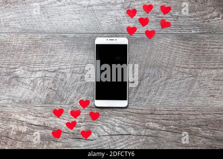 Valentinstag, Telefon auf Holz grauen Hintergrund, mit roten Herzen, die Liebe, die Verbindung zwischen den beiden, geeignet für Werbung einfügen Text Stockfoto