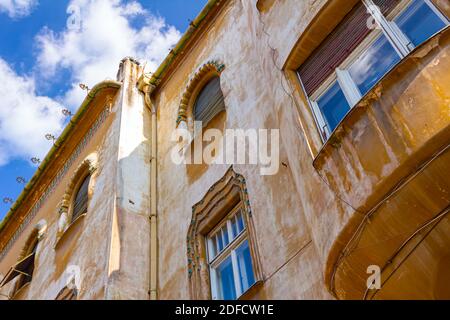 Blick von unten auf gelb dekorierte Fassade mit dekorativen Fenstern, Außenansicht eines alten Gebäudes. Stockfoto