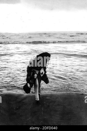 1960s 1970s Outdoor Meer junge Frau in schwarz und weiß allein am toskanischen Strand von Castinglioncello. Italien. Scannen von Kratzern und Flecken Stockfoto