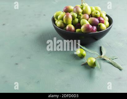 Frisch gepflückte rohe grüne Oliven in schwarzer Schale Stockfoto