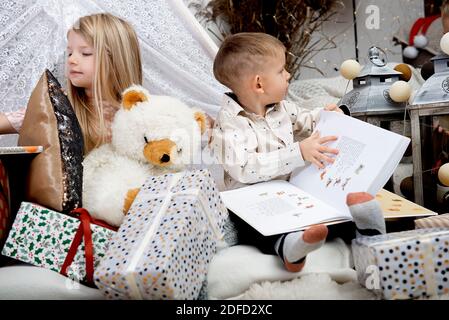Zwei Kinder Kinder lesen Buch zwischen Weihnachten Geschenk-Boxen in einem dekorierten Haus.Frohe Weihnachten und frohe Feiertage! Stockfoto