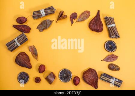 Flacher Lay-Rahmen für Herbstsaison mit Platz für Textkopien. Draufsicht auf die Komposition mit farbenfroher Herbsternte und trockenen Blättern, auf gelbem Hintergrund. Stockfoto