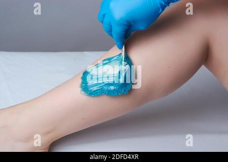 Das Verfahren shugaring Beine.die Anwendung von blauem Zucker paste.depilation in Der Salon Stockfoto
