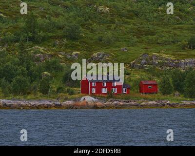 Traditionelles norwegisches Holzhaus mit rot bemalter Fassade am felsigen Ufer der Raftsundetstraße auf der Insel Austvågøya, Lofoten, Norwegen. Stockfoto