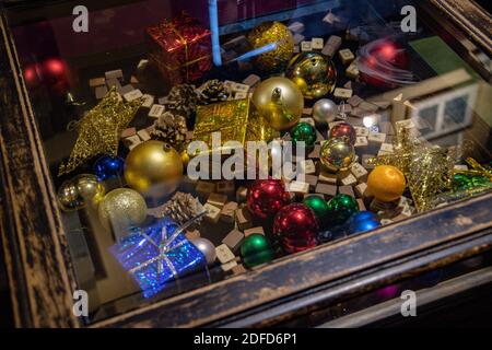 Vintage Couchtisch mit bunten Weihnachtskugeln, brokatumwickelten Weihnachtsgeschenken und Mahjong Holzwürfeln unter Glas-Tischplatte mit verwackelten Reflexen. Tr Stockfoto